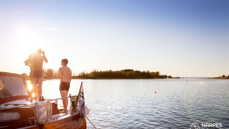Tre personer står i en förtöjd båt