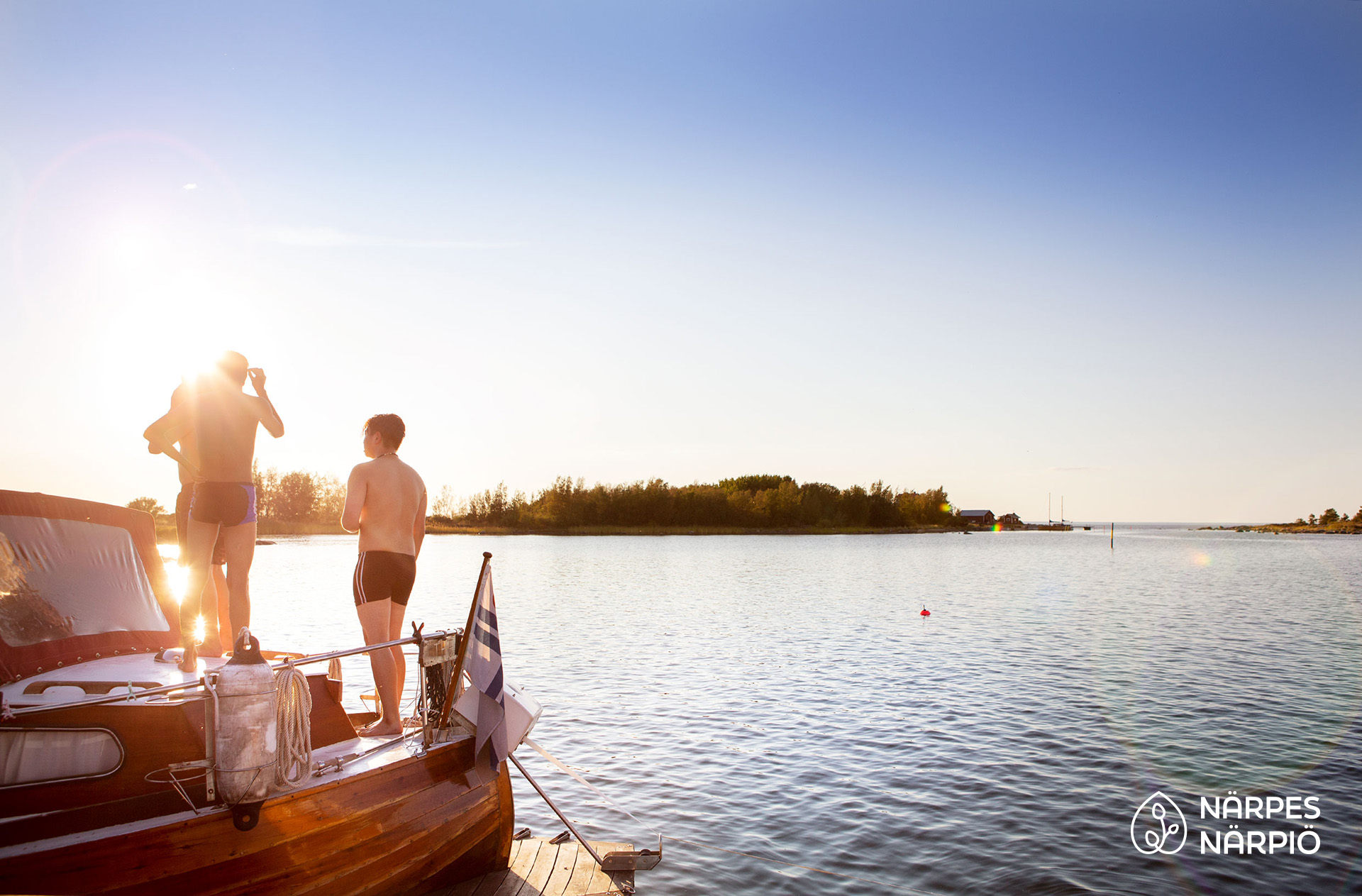 Tre personer står i en förtöjd båt