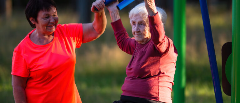 Två äldre kvinnor tränar vid utegym