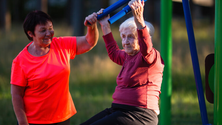 Två äldre kvinnor tränar vid utegym