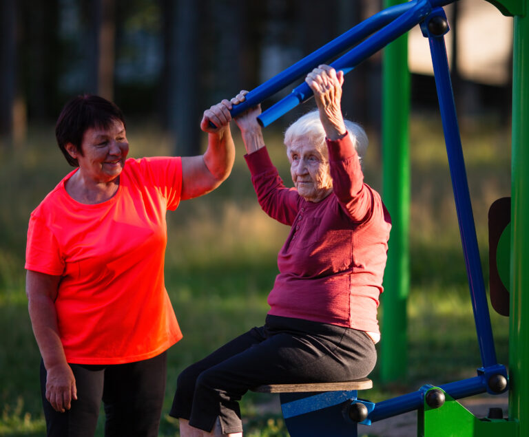 Två äldre kvinnor tränar vid utegym