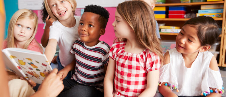 Lågstadieelever lyssnar då lärare läser högt ur bok