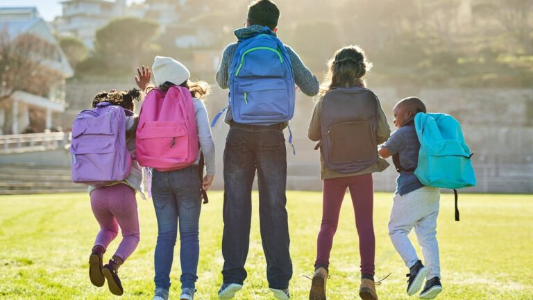 Oppilaita joilla on reppuja selässä ovat ulkona