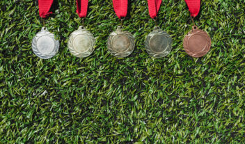 Ylhäältä otettu kuva erilaisista mitaleista, jotka makaavat nurmikolla