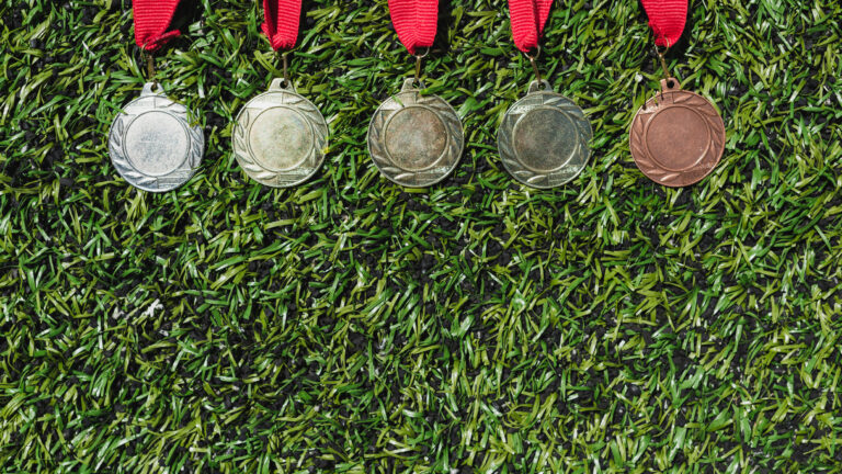 Ylhäältä otettu kuva erilaisista mitaleista, jotka makaavat nurmikolla