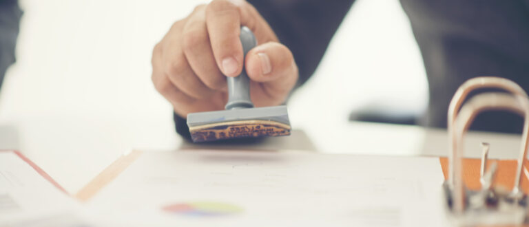 En hand stämplar ett dokument