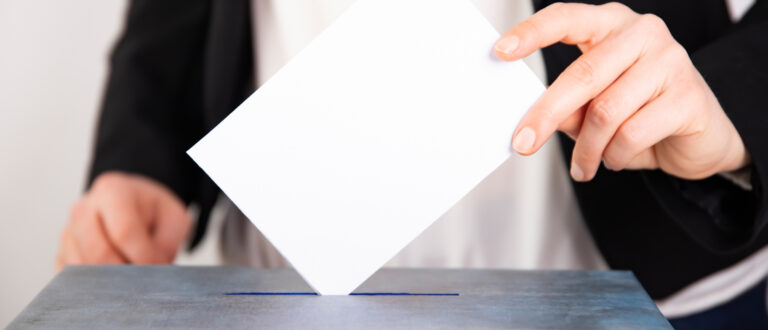 En person lägger sin röst i en röstlåda