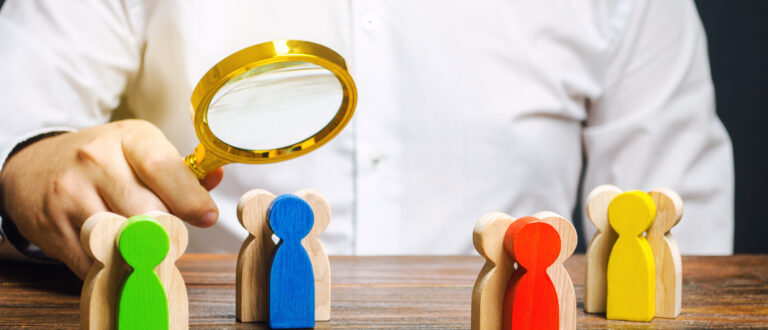 En människa granskar några grupper av träfigurer med ett förstoringsglas