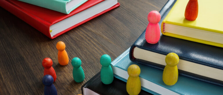 Spelpjäser i olika färger som placerats ut på en hög av böcker