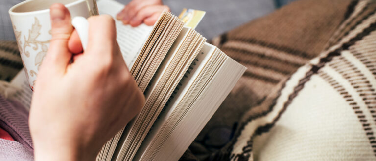 Kvinna som dricker te och läser en bok